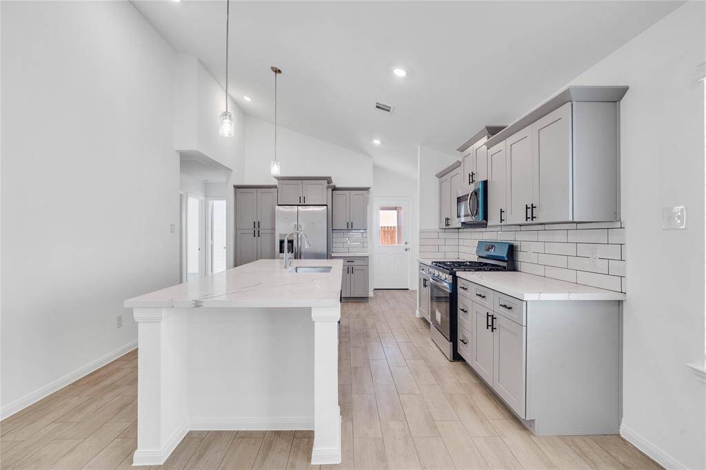 This kitchen will not disappoint! Your family and guests will enjoy many nights of fun, food and entertainment with ample counter space and kitchen island for setting up a wonderful array of provisions. This view of this gorgeous kitchen showcases SS appliances, silestone countertops, beautiful tile backsplash, gas range, double oven, high ceiling, recessed and pendant lighting and tile floors!