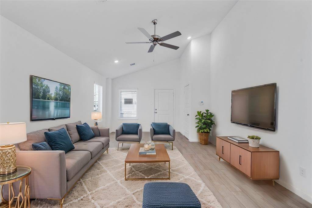 This living room is more like a GREAT room featuring soaring high ceilings, tile floors, recessed lighting, ceiling fan, and plenty of windows providing a natural light throughout the home. *virtually staged*