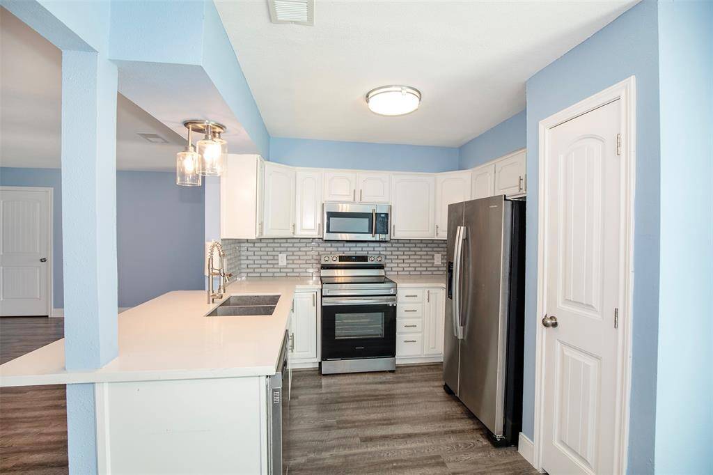 The kitchen features beautiful white cabinetry and stainless appliances.