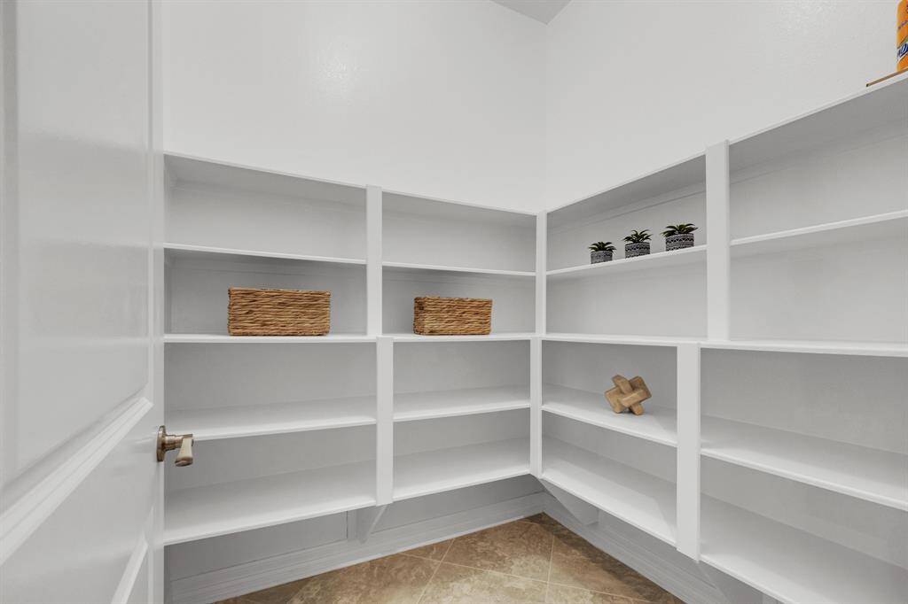 This is a spacious, built-in corner pantry with white shelving, suitable for ample storage in the kitchen area.