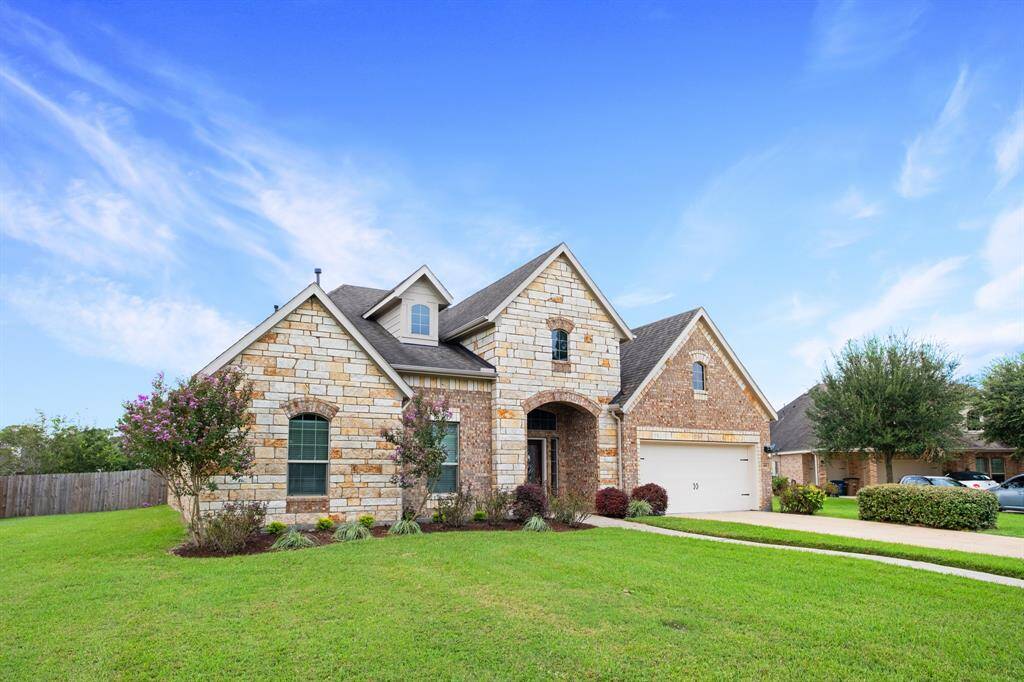 Charming single-family home featuring stone and brick façade, arched entryway, two-story elevation, well-manicured lawn, and an attached two-car garage.