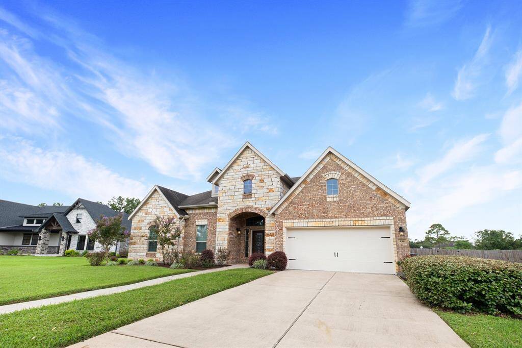 This is a single-story brick home featuring a two-car garage, arched entryway, well-maintained lawn, and a welcoming suburban atmosphere under a clear blue sky with wispy clouds.