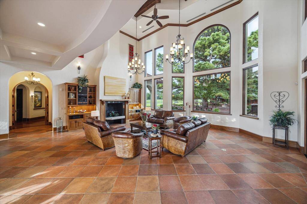 The two-story wall of windows creates abundant natural light and allows for a captivating view of the lush landscape and resort style pool beyond. Double French doors lead directly to the outdoor patio area.