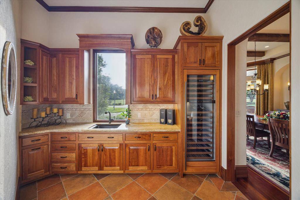 A charming pocket door leads to the butler’s pantry off the formal dining room. Caterers will feel spoiled to have this dedicated space from which to prepare and serve. The butler’s pantry boasts abundant cabinetry with granite countertops as well as sink and full-size wine refrigerator with individualized settings for reds and whites.