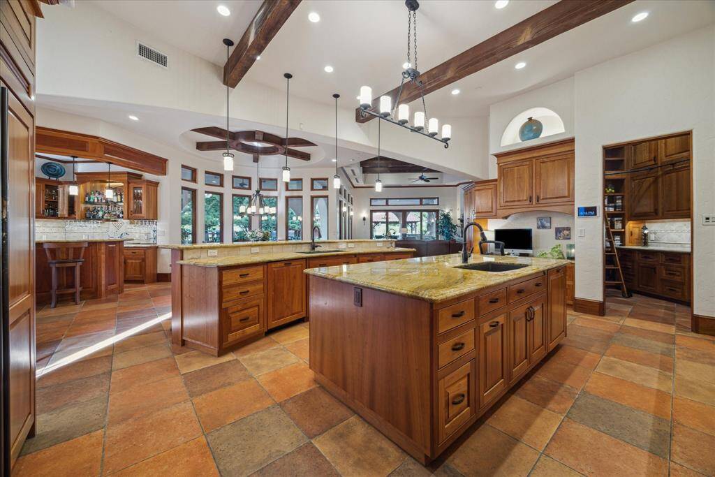 Beyond the formal living areas, the culinary space becomes the nucleus from which everything flows. Two spacious islands topped with granite slabs and each featuring its own full size sink and dishwasher, create a functional and beautiful space. One island also serves as a breakfast bar accommodating 4-6 for coffee, lunch or conversation.