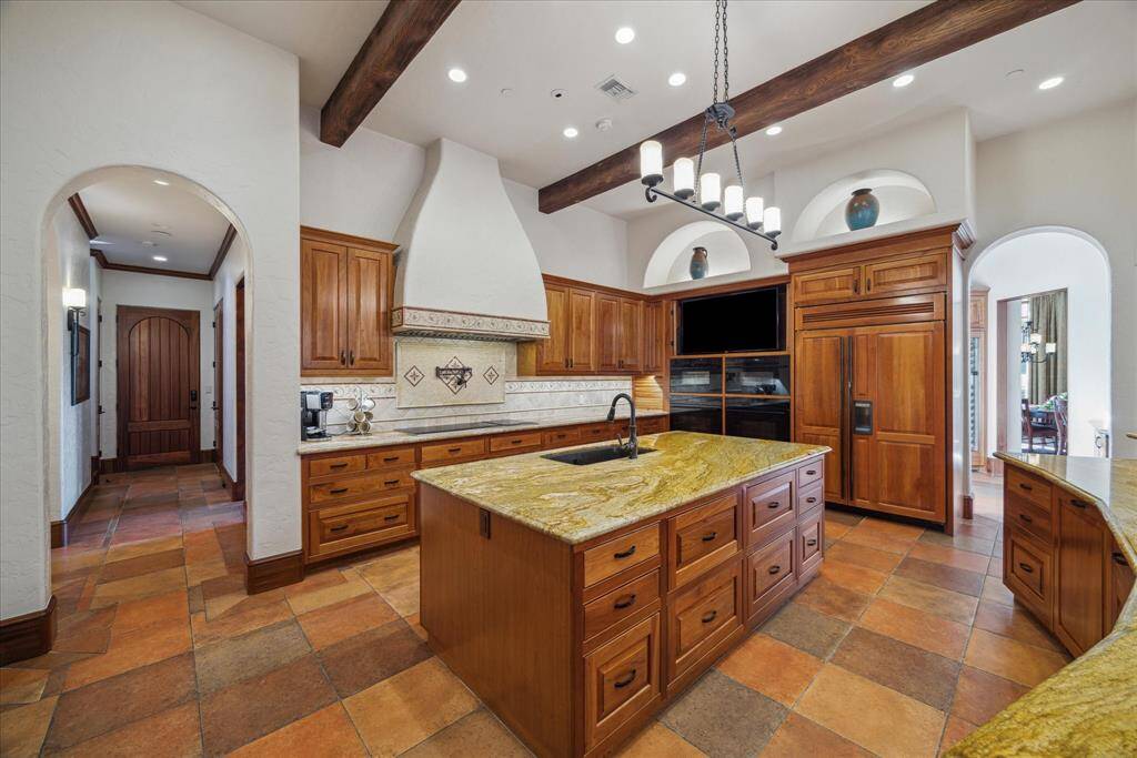 The curved, towering vent hood is the scene stealer in this luxurious kitchen, perched above an oversized induction cooktop featuring six burners and two additional electric burners as well as a pot filler. The chef’s ideal working triangle is created from the sinks to the built-in Sub-Zero refrigeration system to the double Wolf convection ovens, Wolf steam oven and Wolf microwave oven. This kitchen is outfitted with the best appliances the market can offer.
