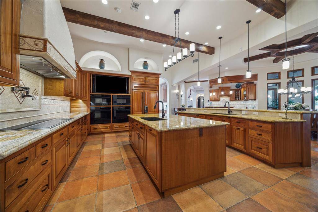Multiple light sources including recessed, hanging pendants, niche and under-cabinet lighting illuminate this richly-hued space. A chef’s desk provides an area to keep daily mail and clutter contained and organized. A pocket door hides a walk-in pantry with open shelving, cabinets and drawers to store cookware and supplies. Store rarely used items on higher shelves easily accessed from the iconic Putnam Rolling Ladder which adds layers of functionality and style to this space.