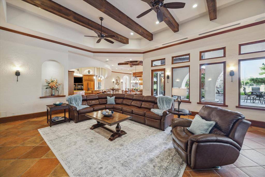 The kitchen eases into the breakfast area, bar and spacious family room for an ideal flow. The light and open family room features oversized beam accents on its 14 foot tray ceiling, warming the space. Dual walls of windows and sliding doors, all topped with transoms, saturate the room in natural light and invite the outdoors in.