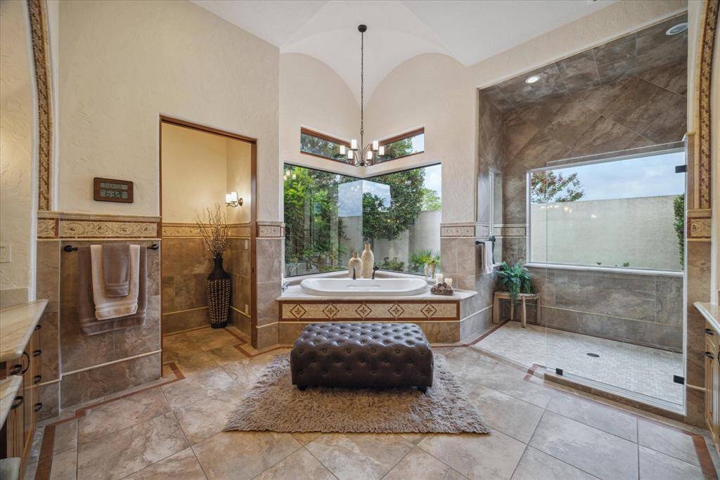 The luxurious primary bathroom is truly elegant! Bathed in natural light, the spacious walk-in shower features a rainfall shower head in addition to two wall heads, a handheld wand and four body sprayers. The Bain Ultra air-jet corner tub is surrounded by plate glass windows overlooking the private garden, fashioning an old world feel with modern luxuries. The Bain Ultra tub maintains the bath at a heated temperature allowing one to linger and relax.