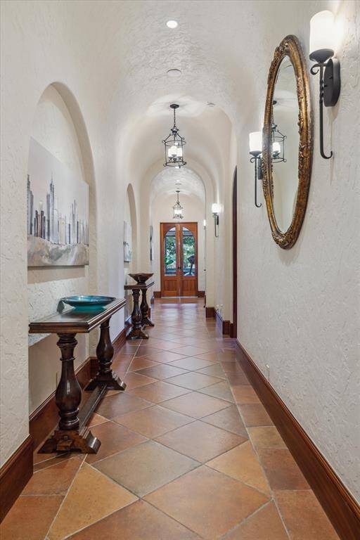 An architecturally pleasing hallway with a barrel ceiling is dedicated to guest quarters. All three guest suites may be accessed here, separate from the primary suite for maximum privacy.  The hallway features 8” baseboards, Saltillo tile floors, wrought iron pendant lights and repeated wrought iron sconces. The guest wing and hallway feature access to the dedicated pool bath, huge linen closet and French doors exiting directly to the pool area.