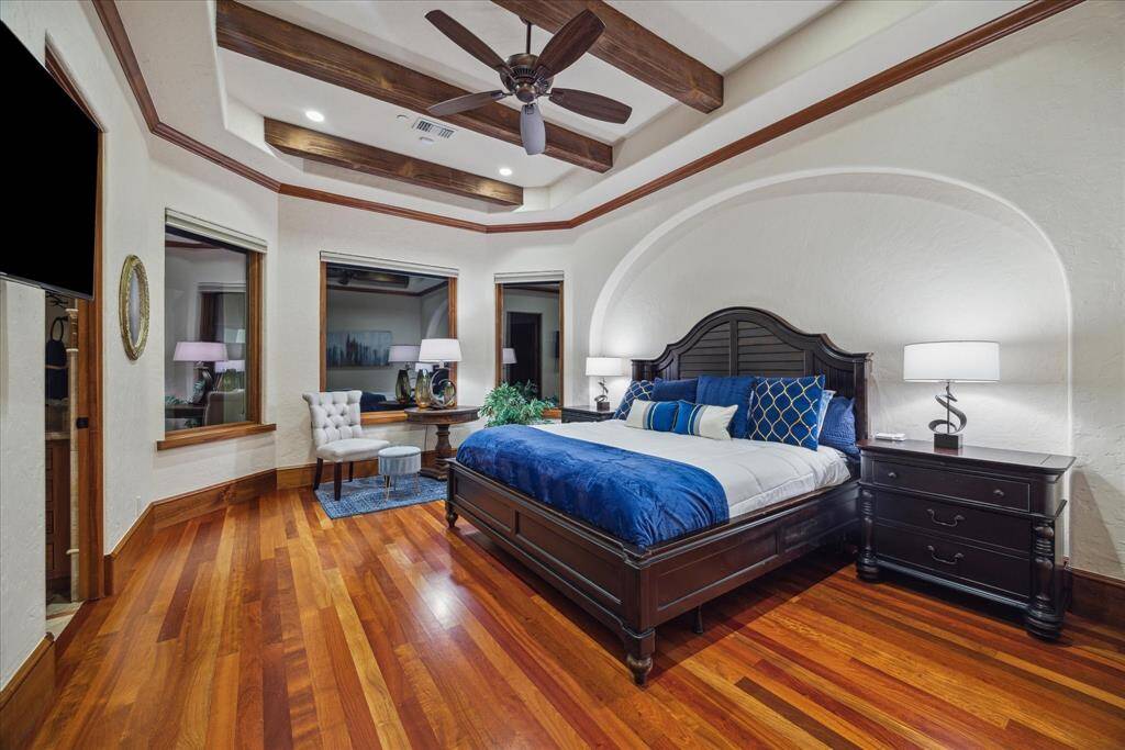 Custom, arched tongue and groove doors reveal the secondary bedroom suites. Bedroom suite 1 boasts wood floors, 8” baseboards, a beamed, tray ceiling, 3 oversized picture windows with motorized Lutron shades and a walk-in closet. It boasts its own private en-suite bath with a walk-in shower and a window to the private garden. The bathroom features oil rubbed bronze hardware, tasteful marble countertops, built-ins and medicine cabinet.  The entire home is also equipped with a central vacuum system.