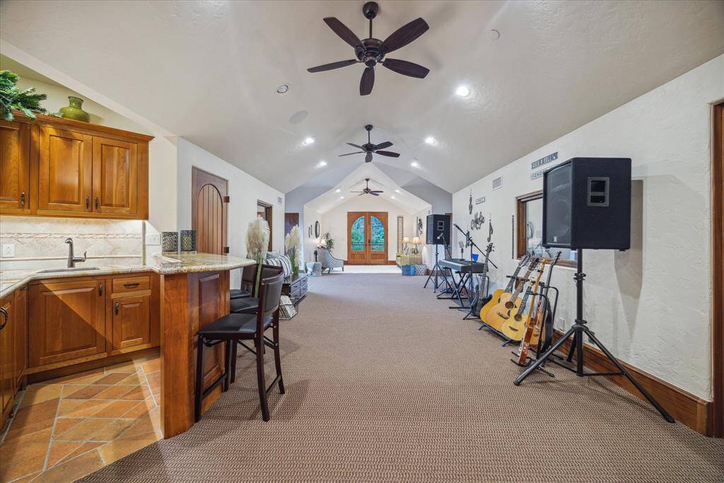 The soundproof recording studio resides in its own wing near the second staircase. A vaulted ceiling provides architectural interest and acoustic properties to this versatile space featuring separate windowed control room and vocal booth. A lounge area is located at the far end of the room with French doors to a balcony. This room could easily function as a game room, studio, fitness center or playroom.