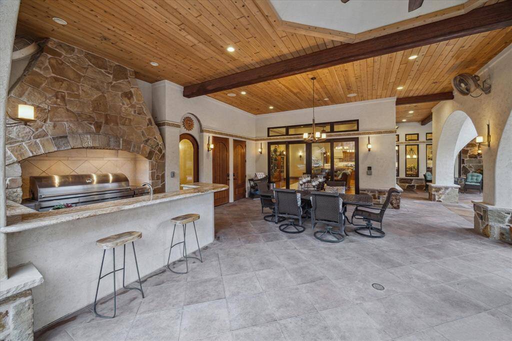 The outdoor living space extends the square footage of this estate further and functions like a resort. The large outdoor living and dining area and patios are finished with tongue and groove ceilings accented by wood beams. A grand stone hearth creates a focal point in the outdoor kitchen and houses the oversized 48 inch wolf grill. Wolf gas burner, sink, refrigerator, ice maker and stainless steel drawer system complete the outdoor kitchen.