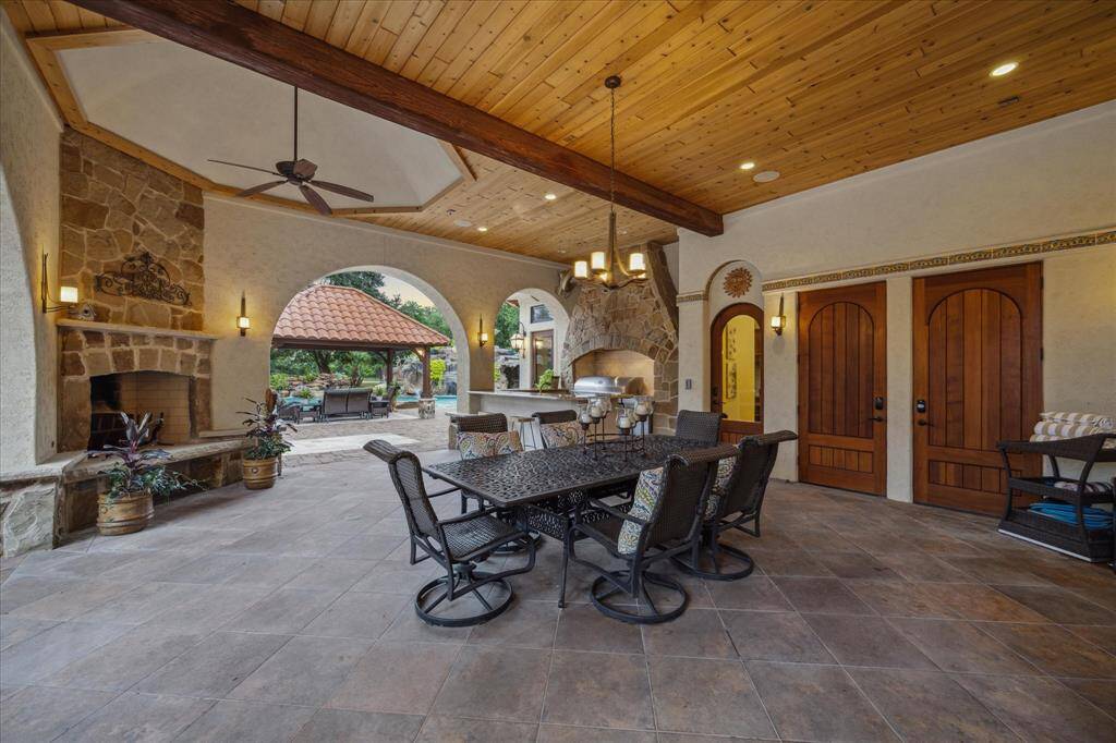 A stone wood-burning fireplace warms the covered patio on crisp nights. Tasteful handmade porcelain tiles trim the area. Wrought iron sconces create a warm glow in the evenings. Patios and pergolas graciously extend the 11,000 square feet further with livable outdoor space for gatherings.