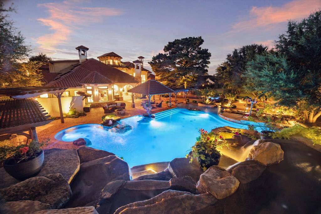 A view of the rear of the home at dusk shows the dramatic impact of the carefully planned lighting and waterpark design.
