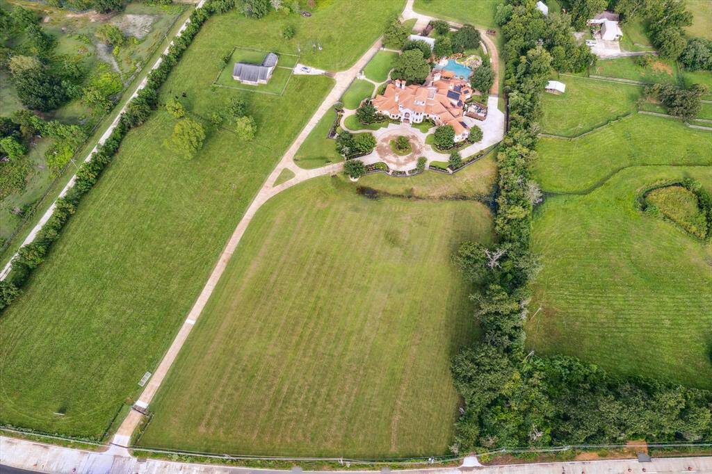 This aerial view showcases the entire 5.778 acres of this custom estate. This property features 65 solar panels, Geothermal heating system, elevator shaft, 10-14’ ceilings, 5 Rheem water heaters, commercial air conditioners and fire sprinkler, 150 KW whole house generator, 2 motorized gates, 2200 square foot 100,000 gallon pool and splash pad, water well and 2 septic systems, and 600 amp electrical service.