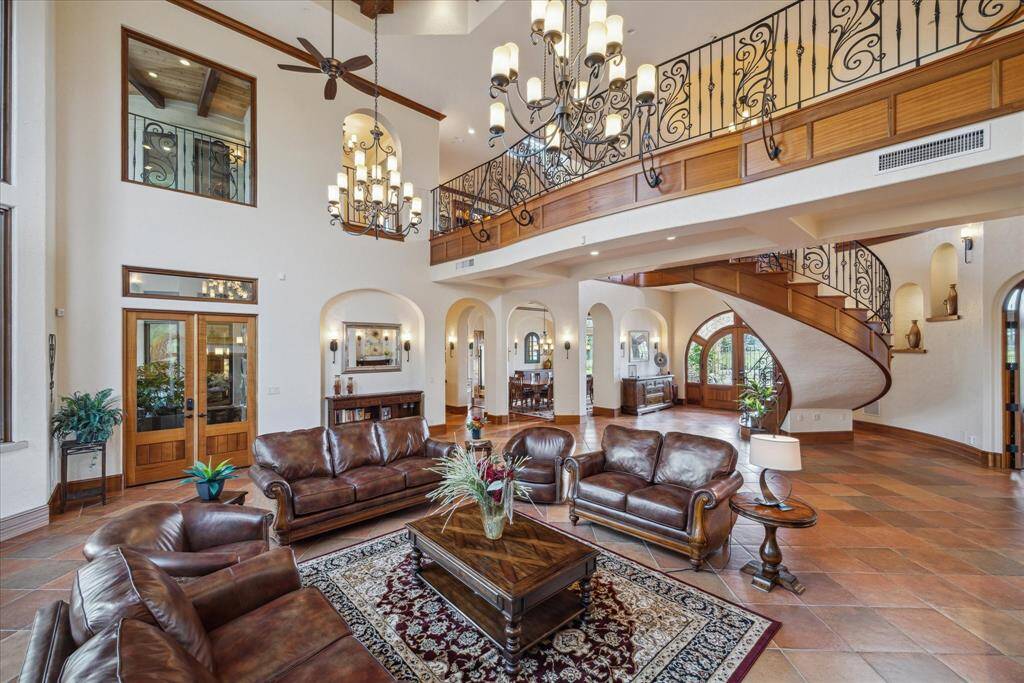 The grand formal living area is located just beyond the formal entry and boasts a coffered ceiling of wood beams and two oversized wrought iron chandeliers. A raised, wood-burning fireplace with a chiseled stone hearth (and gas ignition) creates a focal point and is flanked by solid wood built-ins.