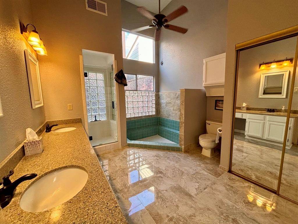 A bright, open primary bathroom with double sinks, a step-down soaking tub, a standup shower, and closet space.