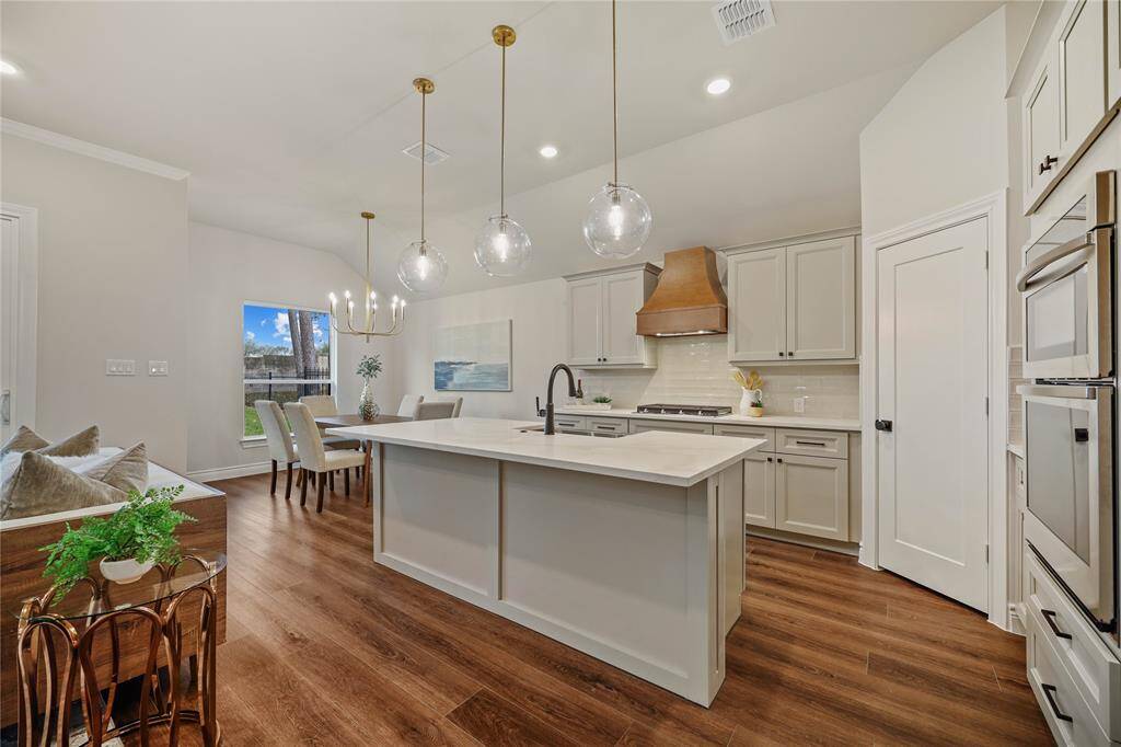 Kitchen with all the touches.  Undercounter lighting, trash pull out, farm house sink, custom wood hood, and oversize pendants.