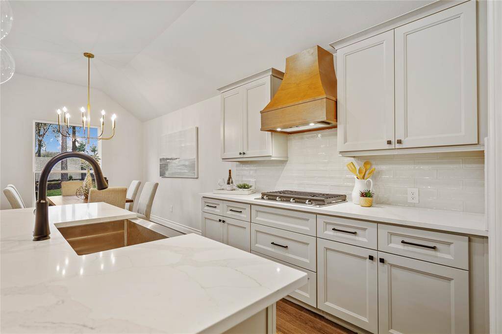 Kitchen with all the touches.  Undercounter lighting, trash pull out, farm house sink, custom wood hood, and oversize pendants.