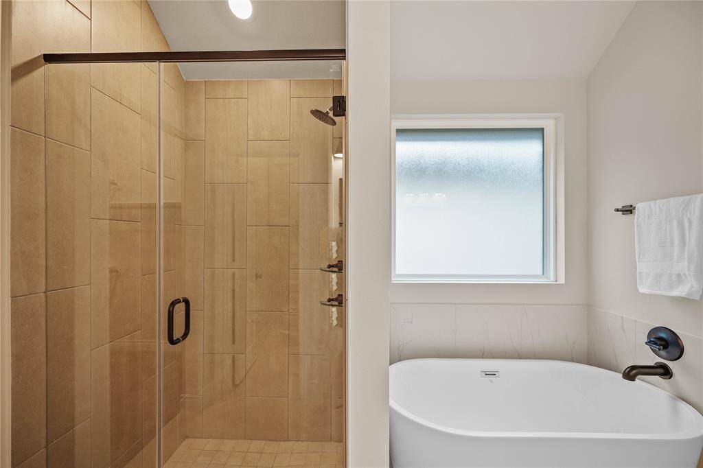 Free-standing master tub with step down shower.