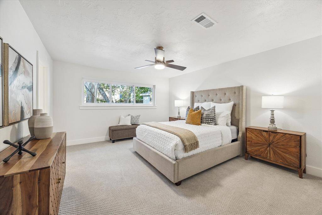 THE PRIMARY SUITE IS SPACIOUS AND FEATURES MODERN CEILING FAN AND PLUSH CARPET.