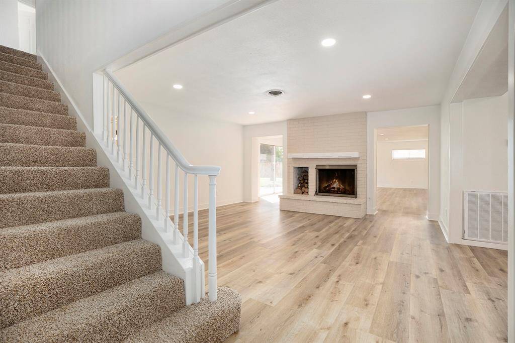 This interior shot showcases a bright, open-plan living area with a cozy fireplace and a staircase leading to the second level. The space features modern flooring and fresh, neutral wall colors, ideal for personalizing to your taste.