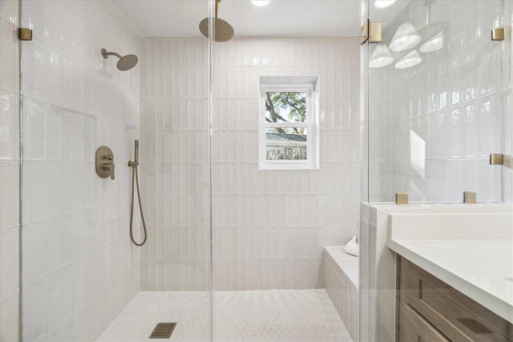 A CLOSE-UP OF THE WALK-IN SHOWER WITH FLOOR TO CEILING TILES AND CUSTOM FIXTURES.