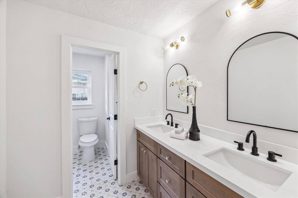 THE SECONDARY BATHROOM FEATURES KARAMEL SHAKER CABINETS WITH DOUBLE SINKS, QUARTZ COUNTER AND DESIGNER MIRRORS.