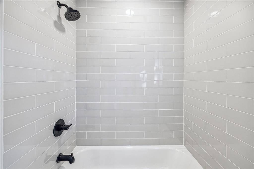 THE SECONDARY BATHROOM BOASTS A SHOWER/TUB COMBO WITH TRENDY SUBWAY TILES.