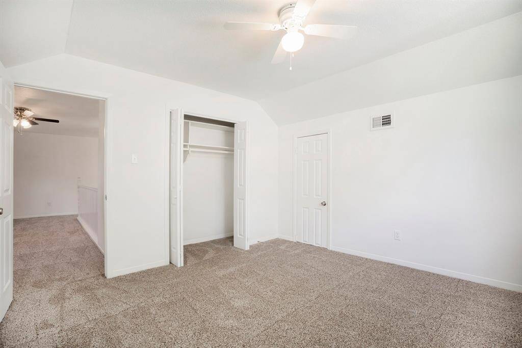 This is a spacious, well-lit upstairs bedroom featuring plush carpeting, a ceiling fan, and ample closet space, with a neutral color palette ready for personalization.
