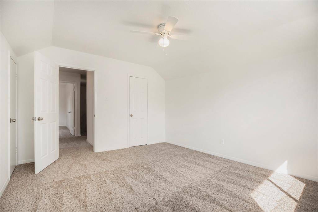 This is a bright secondary upstairs bedroom with neutral walls and carpet, featuring a ceiling fan with a light fixture.