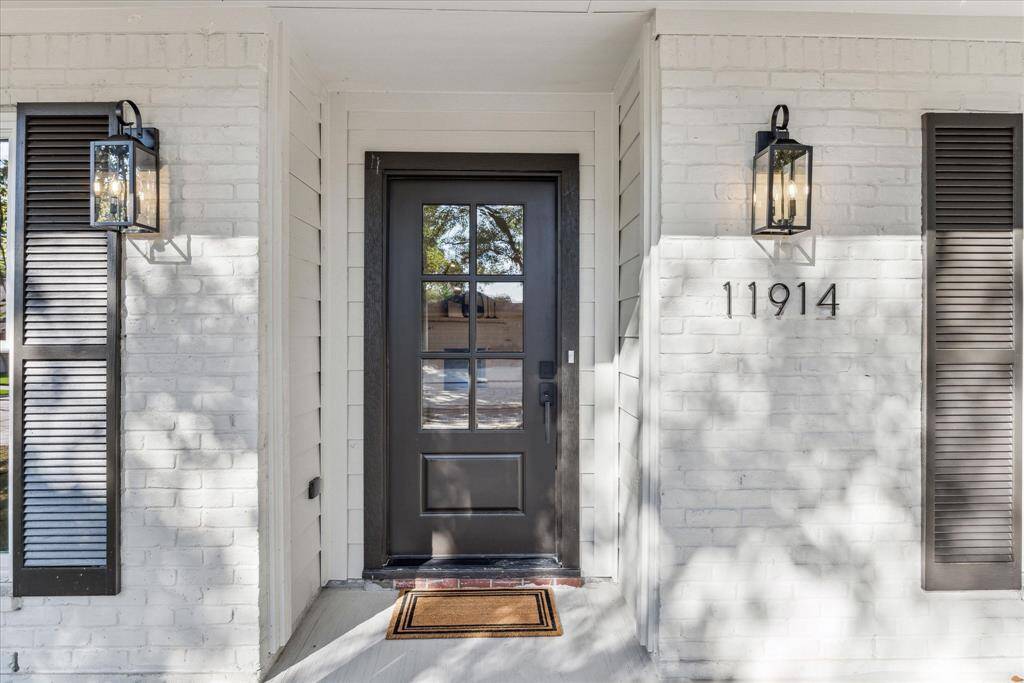 THE COVERED PORCH FEATURES CUSTOM LANTERNS AND RECENT GLASS PANELED FRONT DOOR.