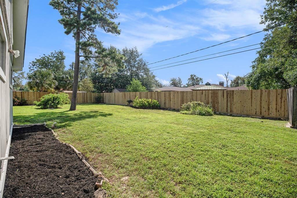 Spacious backyard with fresh landscaping, a well-maintained lawn, and a new privacy fence, offering ample outdoor space for relaxation and activities.