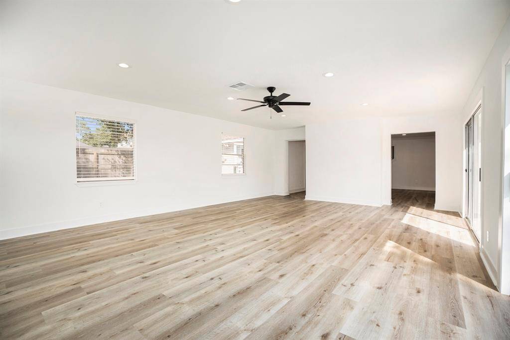 Spacious family room with seamless indoor-outdoor flow, featuring dual sliding doors opening onto a sunlit patio.