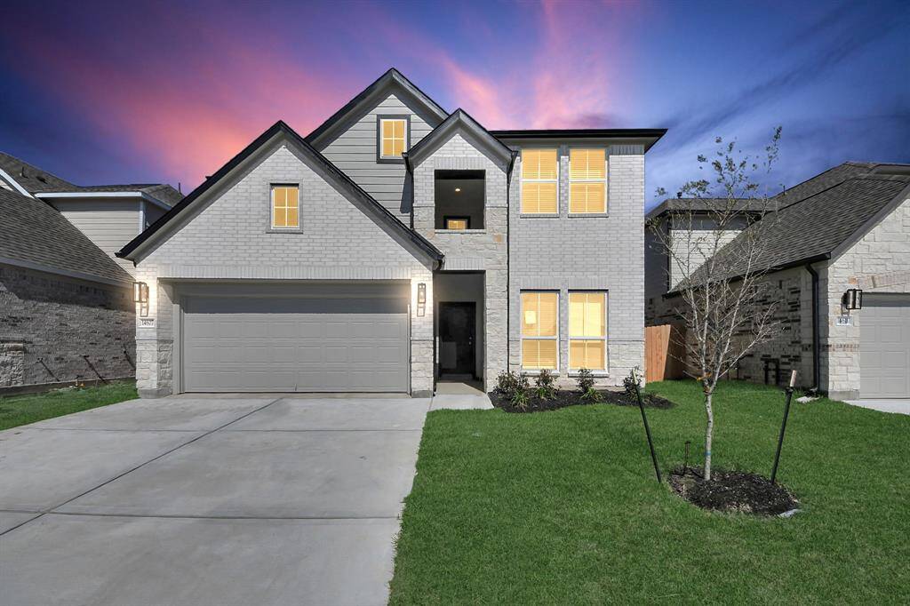 Behold a lush landscape, impeccably maintained yard, and a premium elevation adorned with captivating brick and stone features.