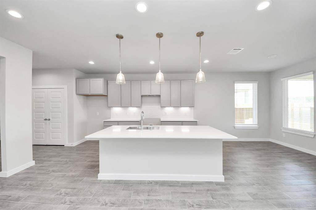 This generously spacious kitchen is a dream realized! With a massive granite island, high ceilings, soft close cabinets, granite countertops, stainless steel appliances, a sleek tile backsplash, recessed lighting, and an extended counter area, it offers both style and practicality. All this opens up to the expansive family room, creating a perfect hub for gatherings.