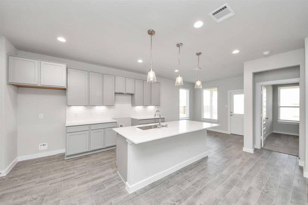 This kitchen is truly a chef's dream! This haven Boasts high ceilings, recessed & pendant lighting, stained wood cabinets, granite countertops, stainless steel appliances, a modern tile backsplash.