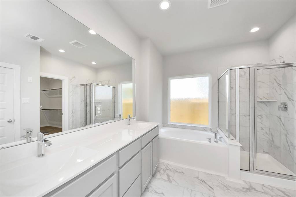 Indulge in a spa-like retreat within the confines of this primary bathroom. Delight in a spacious walk-in shower enveloped in stylish tile surround and unwind in a separate garden tub adorned with custom detailing.