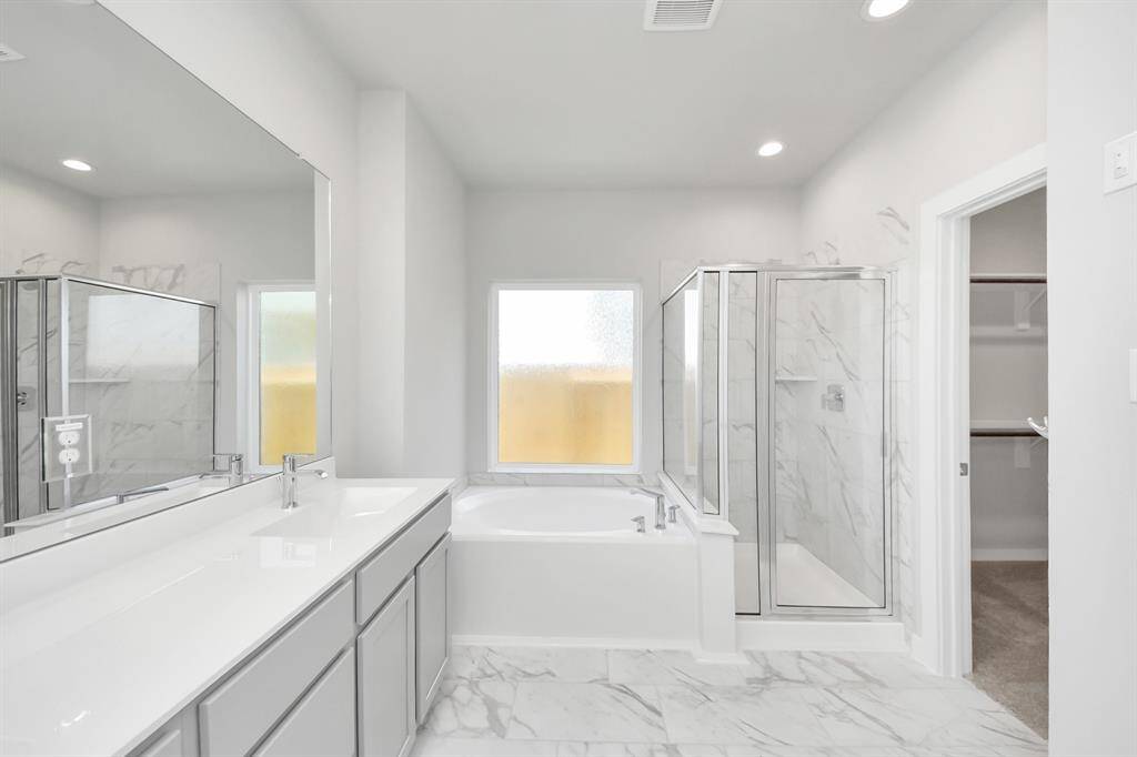 Elevate your daily routine at the elegant vanity, now equipped with double sinks, light countertops, modern hardware, and beautiful recessed lights.