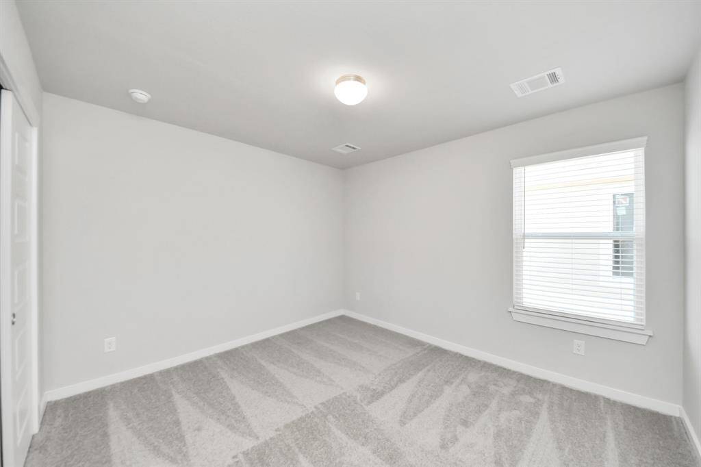 Secondary bedroom features plush carpeting, large windows that let in plenty of natural light, bright paint, and spacious closets.