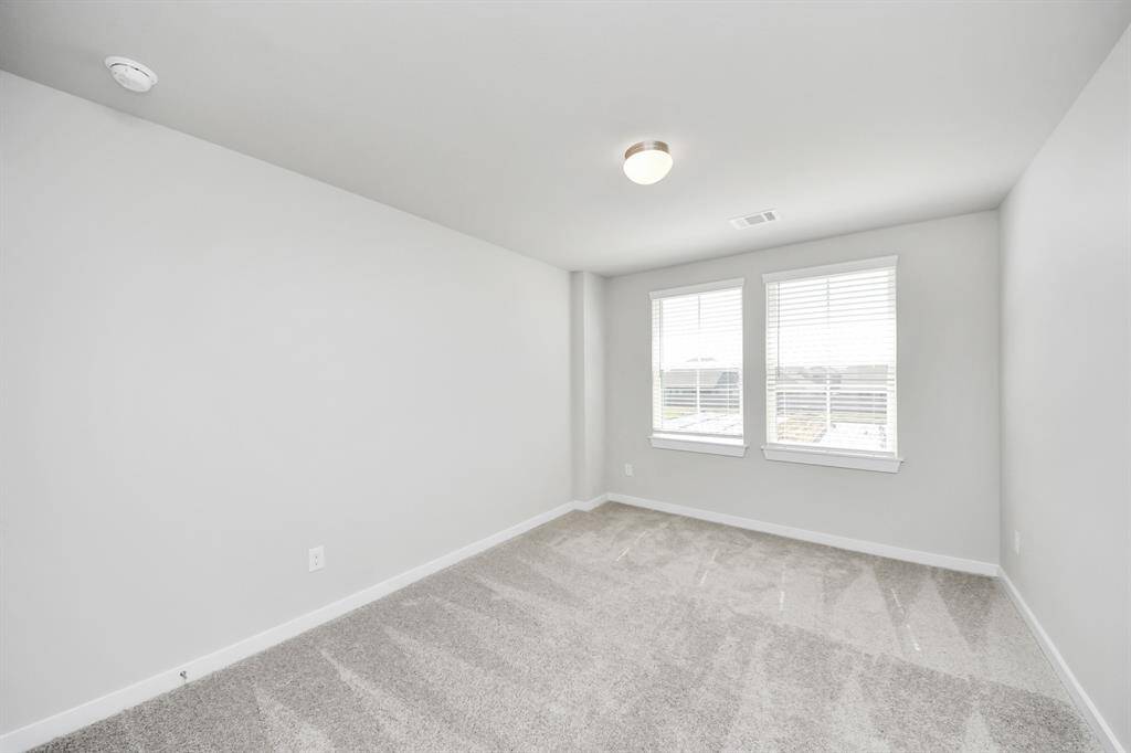 Secondary bedroom features plush carpeting, large windows that let in plenty of natural light, bright paint, and spacious closets.