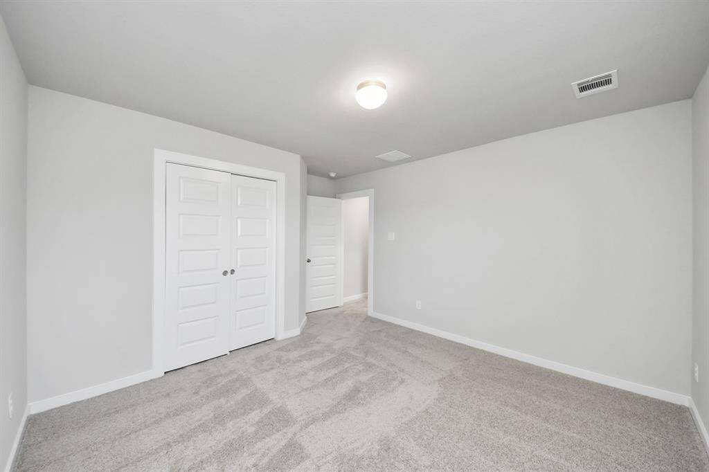 Secondary bath features tile flooring, bath/shower combo with tile surround, light stained wood cabinets, beautiful light countertop.