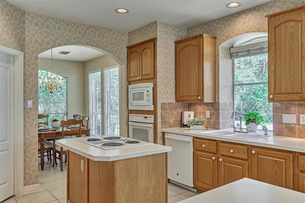 Kitchen has walk-in pantry, undercabinet lighting, and an expansive utility room along with a pretty view from the sink