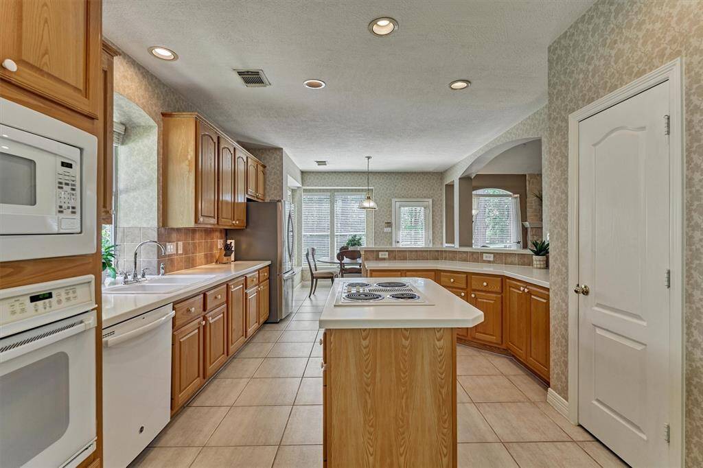 Kitchen has walk-in pantry, undercabinet lighting, and an expansive utility room along with a pretty view from the sink