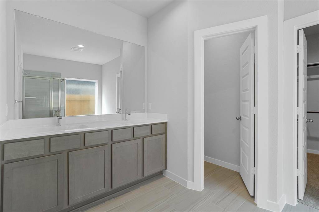 This primary bathroom is definitely move-in ready! Featuring stained cabinets with light countertops and dual vanities, spacious walk-in closet with shelving, high ceilings, custom paint, sleek and modern finishes.