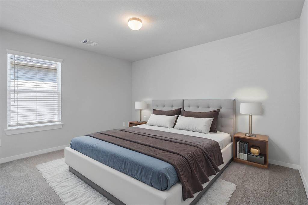 Secondary bedroom features plush carpet, neutral paint and a large window with privacy blinds.