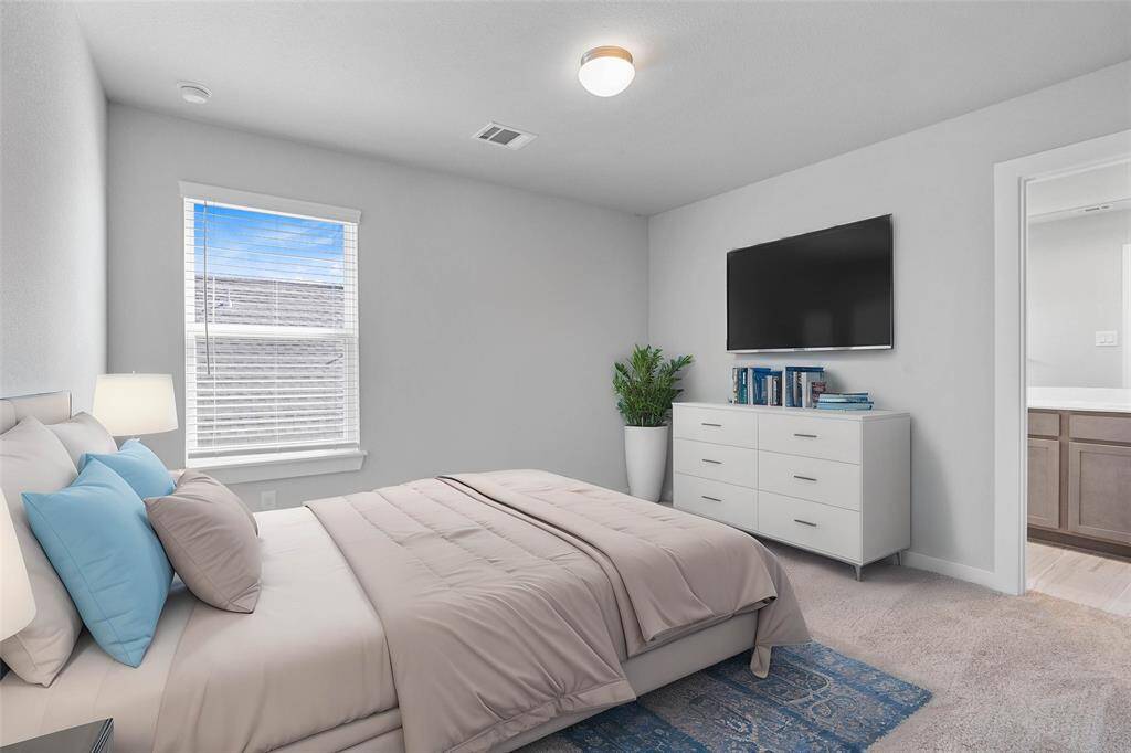 Secondary bedroom features plush carpet, neutral paint, large window with privacy blinds, and access to its own private secondary bathroom.