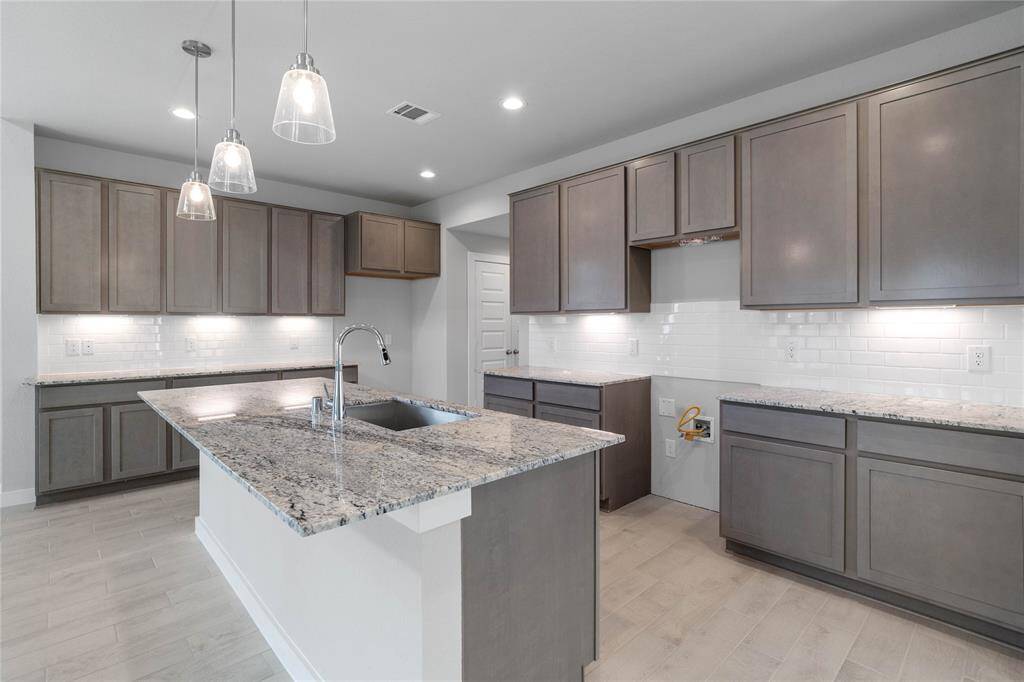 This stunning kitchen displays such beautiful stained cabinets, custom neutral paint, granite countertops, modern backsplash, oversized kitchen island with extra storage, breakfast bar, recessed and pendant lighting, high ceilings and walk in pantry.