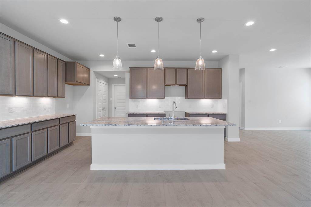 Additional view of this beautiful and spacious kitchen featuring the gorgeous large island with extended granite countertop for breakfast bar and pendant lighting.